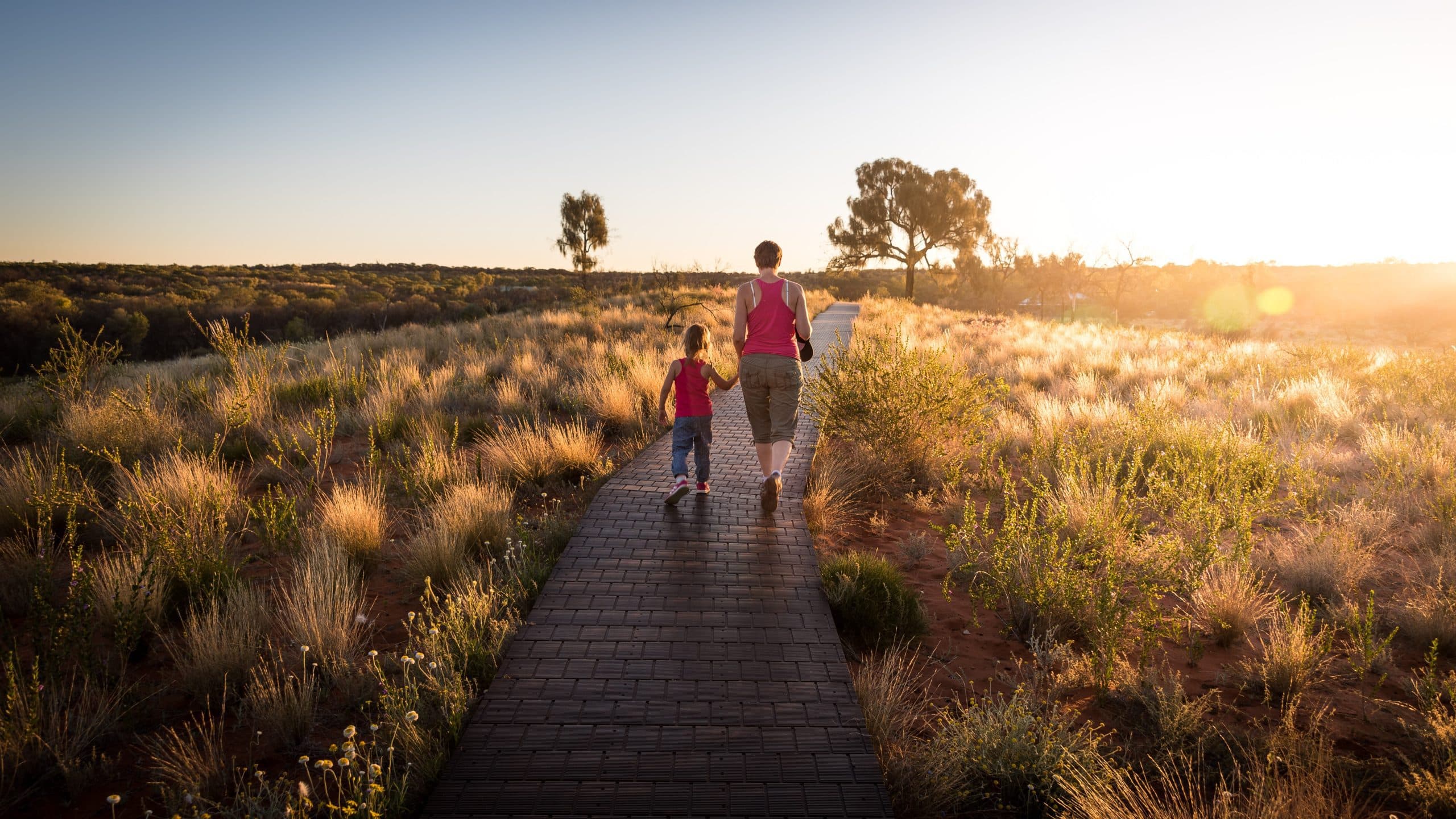 A mother and child walking at sunset.