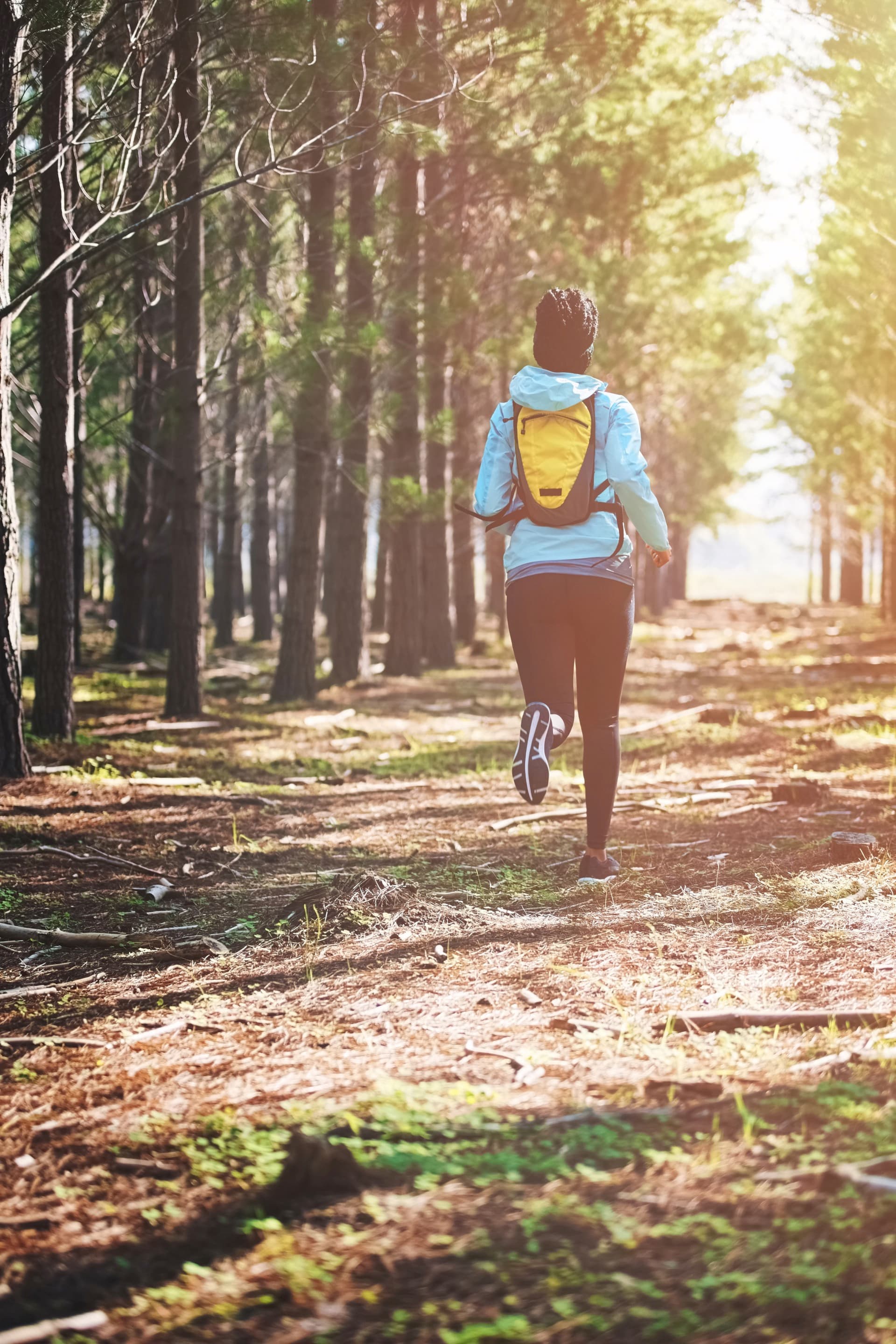 A woman running through wooded trails, picture of mobility.